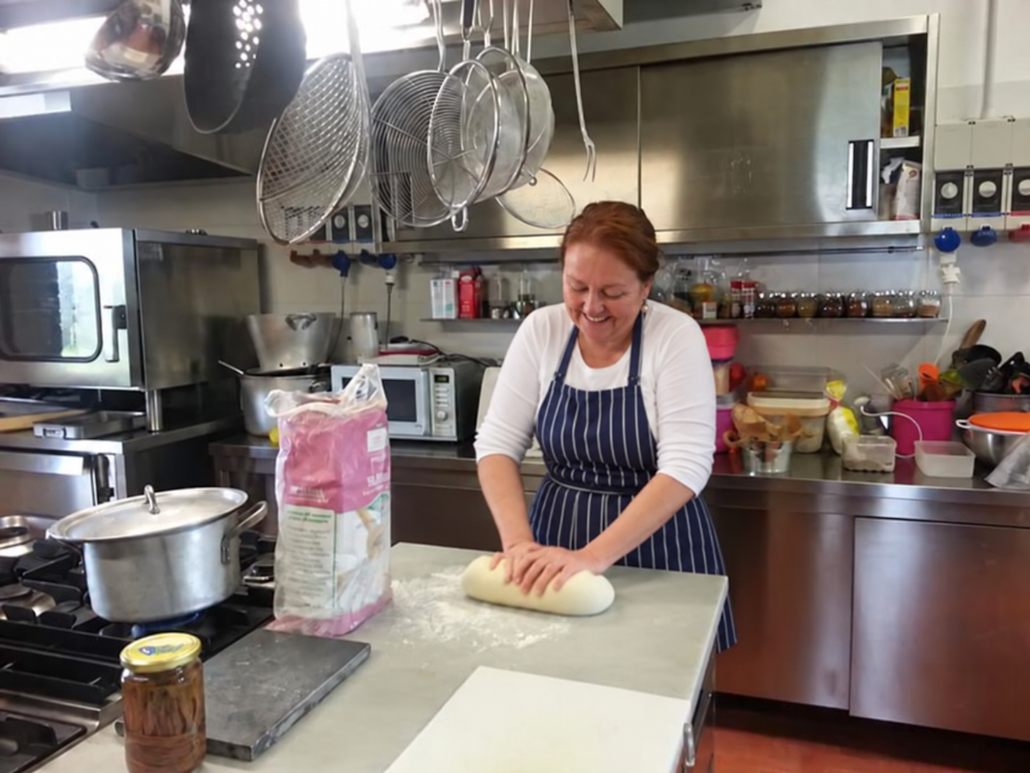 Patrizia kneading bread dough in a working kitchen